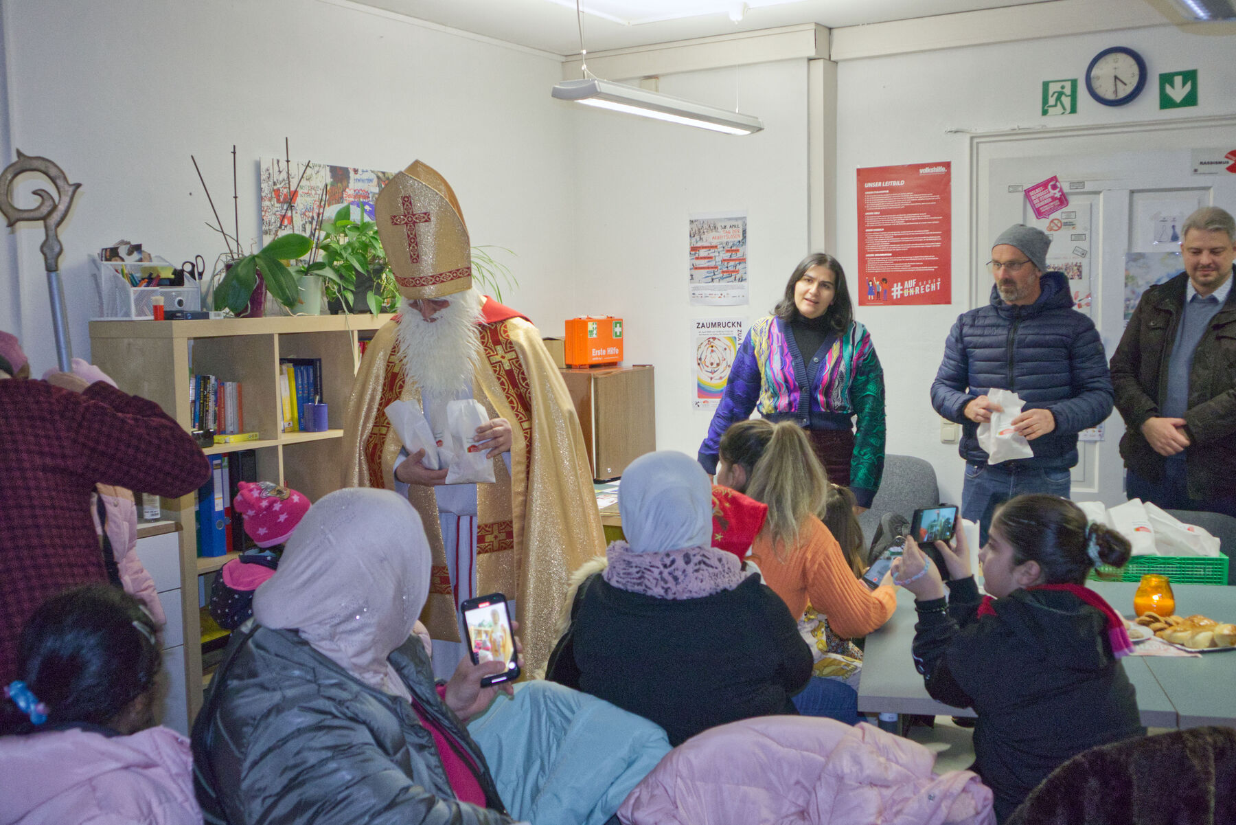 Der Nikolaus übergibt seine Gaben an die kleinen und großen Besucher:innen bei Wohnen im Dialog in Traun.