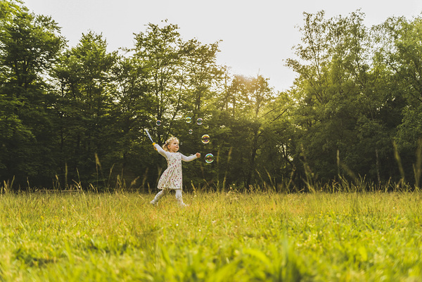 Girl on meadow surrounded by soap bubbles