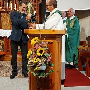 Diakon und Pastoralassistent bedankt sich im Namen der Pfarre mit Wein und einem Gutschein.