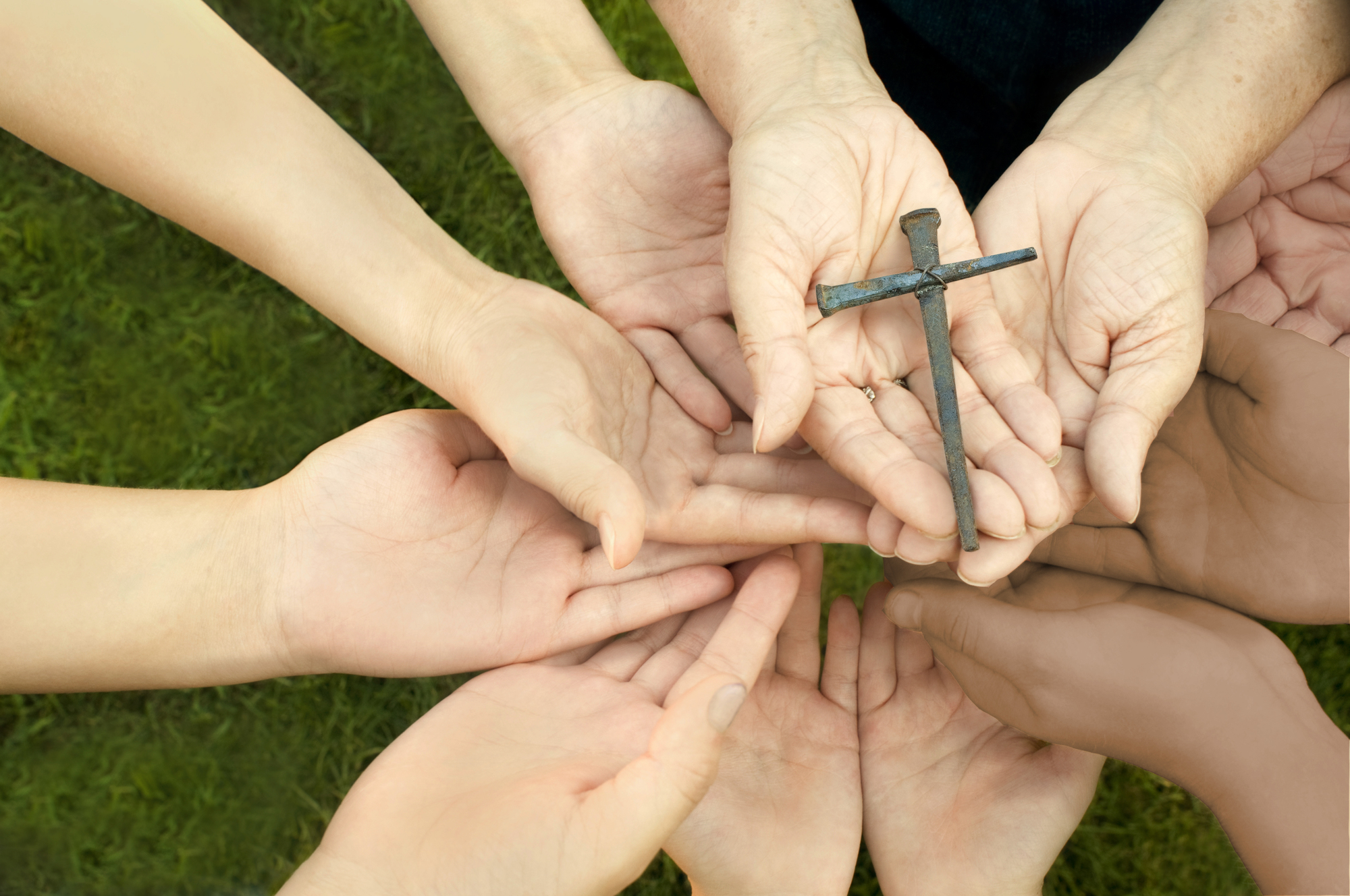 'Hands from people of all ages from children and teenagers to adults and the elderly, hands holding a handmade cross, made from old nails (shallow DOF with focus on the cross). Please see some similar pictures from my portfolio:'