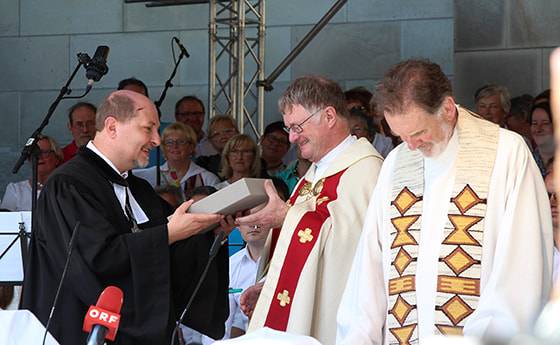 Superintendent Gerold Lehner (l.) überreichte Bischof Manfred Scheuer als Geschenk eine revidierte Übersetzung der Luther-Bibel. Dompfarrer Maximilian Strasser (r.) freute sich mit. © Diözese Linz