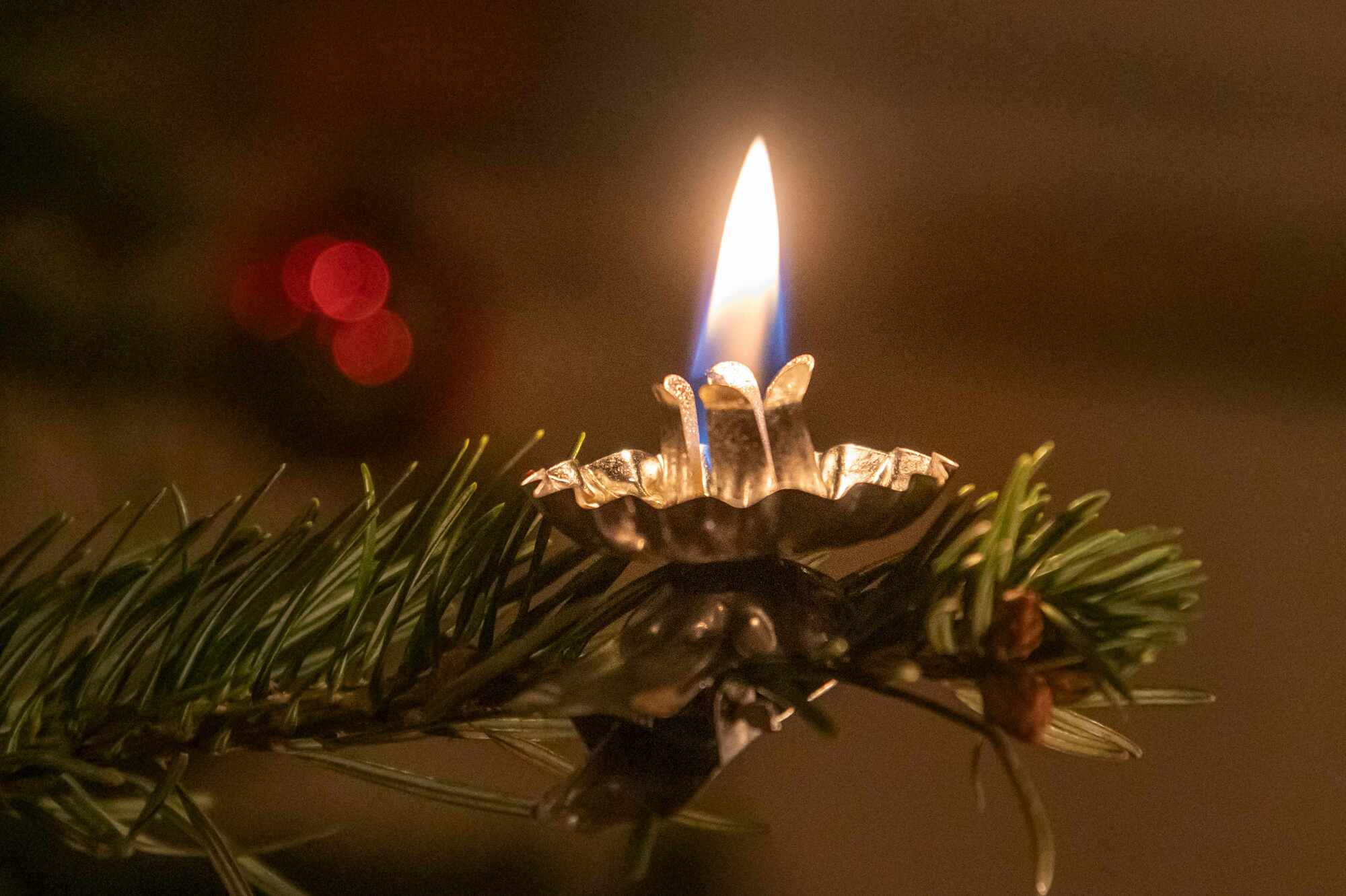 Ausschnitt einer brennenden Kerze auf einem Christbaum Zweig